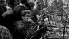 Sie stehen vor einem 3 mal 9 m großen Schwarzweißfoto. Es zeigt eine Großaufnahme von protestierenden Menschen an einem Stacheldrahtzaun. Auf der linken Seite des Zauns stehen die Demonstranten, auf der Rechten stehen ihnen Polizisten gegenüber. Das Foto zeigt Kalkar im September 1977.