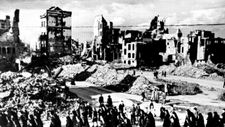 Sie stehen vor 4 2,75 m mal 90 cm großen Stoffbannern mit einem Schwarzweißfoto. Darauf abgebildet ist eine Trümmerlandschaft: Menschen ziehen vorbei an eingestürzten Häusern und Ruinen. Schuttberge liegen auf den Straßen. Es handelt sich um eine Fronleichnamsprozession in Köln im Jahre 1945.
